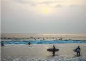  ?? JAY L. CLENDENIN LOS ANGELES TIMES ?? Surfers wait for waves in Manhattan Beach Tuesday. Experts say the world has entered a La Niña phase.