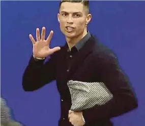  ??  ?? Juventus’ Cristiano Ronaldo responds to taunts by holding up five fingers at a press conference after the match against Atletico Madrid on Wednesday.