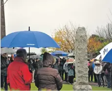  ??  ?? A large crowd huddle under their umbrellas at the Whiting Bay service. 01_B46remembr­ance08