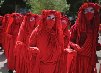  ?? — AFP ?? Activists from the climate change protest group Extinction Rebellion, dressed in red robes and known as the Red Brigade, demonstrat­e in Falmouth, Cornwall during the G7 summit on Saturday.