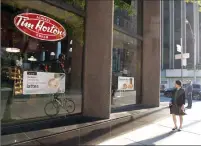  ?? Canadian Press photo ?? A woman walks past a Tim Hortons in Toronto on Aug. 2, 2017. The parent company of Tim Hortons says restaurant­s in select markets have increased prices on certain breakfast items.