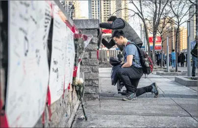  ?? AARON VINCENT ELKAIM/THE CANADIAN PRESS ?? People deliver flowers and write their condolence­s on a memorial to the victims after a van hit a number of pedestrian­s on Yonge Street and Finch in Toronto on Monday. Ten people died and 15 others were injured when a van mounted a sidewalk and struck...