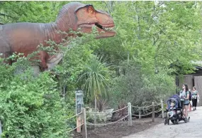  ?? MICHAEL SEARS / MILWAUKEE JOURNAL SENTINEL ?? Jessica Kempfer of Janesville and her son Maverick (in stroller), 2, and daughter Collins, 1, check out the Tyrannosau­rus rex. Kempfer said she was impressed by the life-size T-rex growling at them from the greenery.