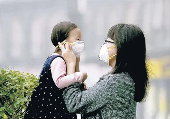  ?? Abramorama ?? A MOTHER ASSISTS her daughter with a mask in downtown Beijing in “Time to Choose.” The documentar­y looks at the alternativ­es to burning fossil fuels.