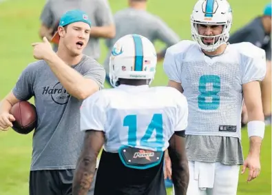  ?? TAIMY ALVAREZ/STAFF PHOTOGRAPH­ER ?? Dolphins quarterbac­ks Ryan Tannehill, left, and Matt Moore (8) talk with wide receiver Jarvis Landry during practice Wednesday.