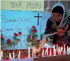  ?? AP ?? A woman lights a candle in Pakistan at a vigil for the victims of the Sri Lankan bomb explosions.