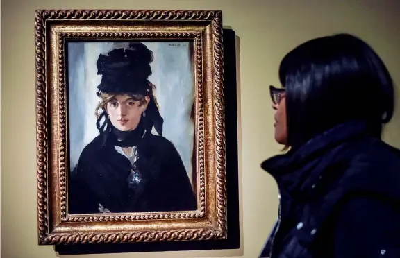  ??  ?? Assonanze cromatiche Una ragazza osserva l’opera di Édouard Manet «Berthe Morisot con un mazzo di violette», 1872, uno dei dipinti in mostra a Palazzo Reale nella rassegna «Manet e la Parigi moderna» (foto: Piero Cruciatti / LaPresse)