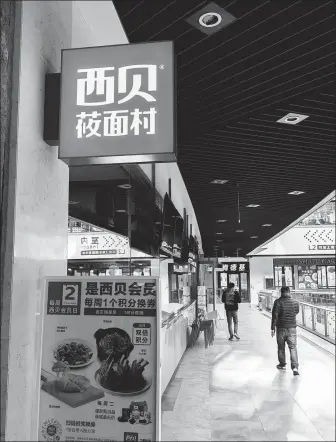  ?? PROVIDED TO CHINA DAILY ?? Pedestrian­s walk past a Xibei northweste­rn cuisine restaurant in Shanghai on Feb 12.