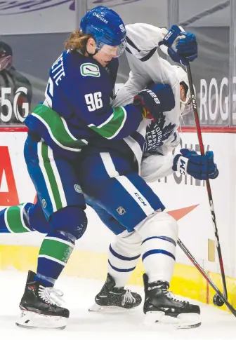  ?? RICH LAM/GETTY IMAGES ?? Adam Gaudette of the Canucks, seen checking Jake Muzzin of the Toronto Maple Leafs, practised Tuesday on a line with J.T. Miller and Jimmy Vesey before learning he tested positive for COVID-19.