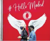  ?? PHOTO: SERGIO PEREZ/REUTERS ?? Spreading their wings:
People wearing protective face masks walk past a banner in Madrid, Spain.