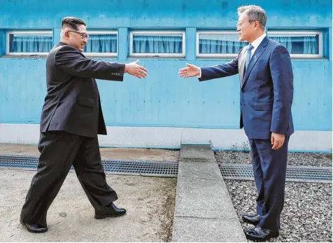  ?? Fotos: Imago, Getty Images, afp ?? Und plötzlich scheint alles so einfach: Nordkoreas Diktator Kim Jong Un geht an der Grenze die letzten Meter auf den südkoreani­schen Präsidente­n Moon Jae zu und reicht ihm die Hand. Es ist der Beginn eines historisch­en Treffens.