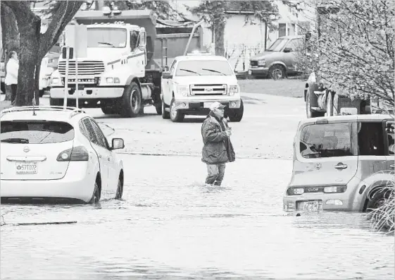  ?? JOHN RENNISON THE HAMILTON SPECTATOR ?? A man walks across a flooded portion of Grand River Avenue in Brantford after the Grand River flooded several areas.