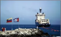  ?? AP/ARIANA CUBILLOS ?? People stand on a breakwater next to Venezuelan (left) and Cuban flags as a ship rolls out a fiber-optic cable suspended from buoys on the Venezuelan coast in this file photo.