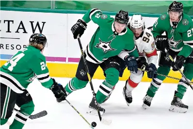  ?? AP Photo/Tony Gutierrez ?? ■ Dallas Stars' Roope Hintz (24), Jamie Oleksiak (2) and Jason Robertson (21) combine to control the puck in front of Florida Panthers left wing Ryan Lomberg (94) in the first period of an NHL game Saturday in Dallas.