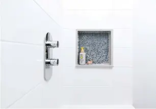  ??  ?? Les contrastes doux entre le blanc et le gris clair du décor se retrouvent dans le coin bain-douche serti d'une jolie niche en mosaïque. Les robinets placés près de l'entrée permettent aux occupants de faire couler l'eau facilement avant de plonger dans le bain.