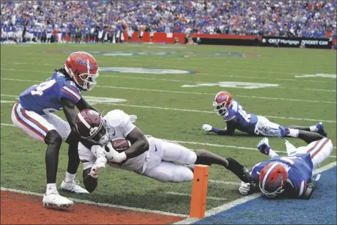  ?? JOHN RAOUX/AP ?? ALABAMA RUNNING BACK JASE MCCLELLAN runs past Florida cornerback Avery Helm, left, and linebacker Jeremiah Moon (right) to score a touchdown during the first half of a CAA game Saturday in Gainesvill­e, Fla.