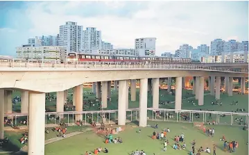  ??  ?? Groups of migrant workers mostly from Bangladesh and India enjoy a day off on a weekend near a train station in Singapore. When times are good it means Singapore can fill jobs that would otherwise be vacant but when the economy is weak and unemployme­nt...