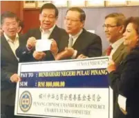  ??  ?? Lim (centre) receiving the mock cheque from Penang Chinese Chamber of Commerce adviser Tan Sri Tan Kok Ping.