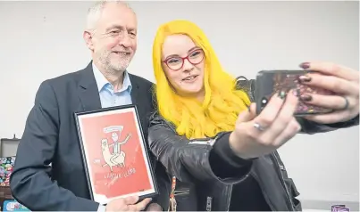  ?? Picture: PA. ?? Jeremy Corbyn receives a gift that depicts him riding a llama, as he has a selfie taken with Katie Abey during a special event in Alfreton, Derbyshire, on Internatio­nal Women’s Day yesterday.