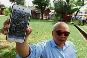  ??  ?? What’s going on?: Yan Lee showing a Google Maps image of the land during a site visit along Burmah Crescent.