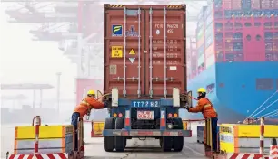  ?? — AFP ?? Workers prepare a container at the port in Qingdao, China’s eastern Shandong province.