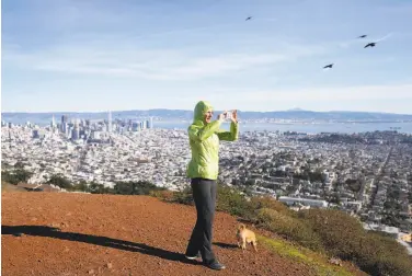  ?? Paul Chinn / The Chronicle ?? Catherine Vowles captures a 360-degree panorama after climbing to the south summit of Twin Peaks.