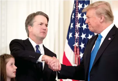  ?? — AFP ?? Kavanaugh shakes hands with Trump after being nominated to the Supreme Court, in the East Room of the White House in Washington.