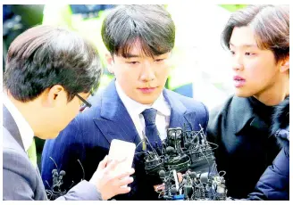  ??  ?? Seungri (centre), member of a popular K-pop boy band Big Bang, arrives at the Seoul Metropolit­an Police Agency in Seoul, South Korea, Thursday. After their stunning retirement announceme­nts, two K-pop stars, including a member of the superstars Big Bang, are facing police questionin­g over a series of interlocki­ng scandals that have roiled South Korea for weeks.