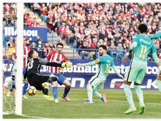  ??  ?? Barcelona’s Argentinia­n forward Lionel Messi, center, scores a goal during the Spanish league football match Club Atletico de Madrid vs. FC Barcelona at the Vicente Calderon stadium in Madrid on Sunday. (AFP)