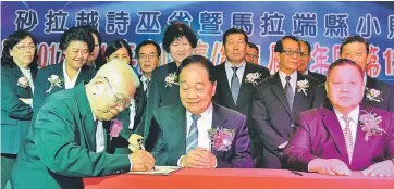  ??  ?? Chiong (seated left) signing an official document while witnessed by Wong (centre), Lim (right) and others.