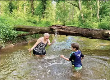  ?? PHOTO COURTESY OF MOLLY SMYRL ?? Betty Evans, of North Coventry, Chester County, and her grandson, Marshall Evans, have a splash fight in the creek at Crow’s Nest Family Camp.