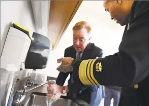  ?? Jessica Hill / Associated Press ?? U.S. Surgeon General Vice Admiral Jerome M. Adams demonstrat­es how long to wash hands with Gov. Ned Lamont during a visit to the state Public Health Laboratory in Rocky Hill on March 2.