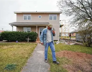  ?? Gerald Herbert / Associated Press ?? Wilfred Trahan talks on his phone Dec. 4 while workers repair siding in the aftermath of Hurricanes Laura and Delta in Lake Charles, La. His family is staying in a hotel in Lafayette.