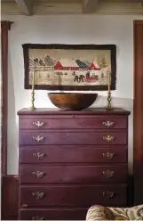  ??  ?? LEFT A deep wooden bowl sits upon a graduated chest of drawers with Chippendal­e willow pulls. The hand-hooked rug shows a nostalgic winter sleighing scene.