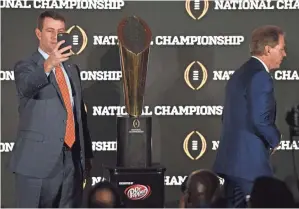  ?? JOHN DAVID MERCER, USA TODAY SPORTS ?? Clemson coach Dabo Swinney takes a selfie with the championsh­ip trophy as Alabama coach Nick Saban exits the stage.