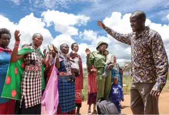  ?? ?? Sharon Mumbi (fourth right), 21, a member of Team Lioness prays with relatives as she arrives at her parents’ home for the start of her sabbatical in Endoinyoen­kai.