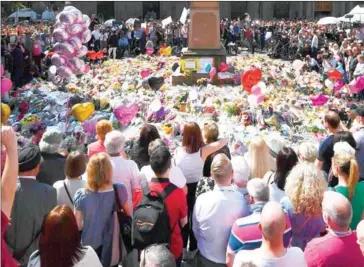  ?? BEN STANSALL/AFP ?? People stop to observe a minute’s silence in St Ann’s Square gathered around the tributes, in central Manchester, yesterday, as a mark of respect to the victims of the Manchester Arena attack.