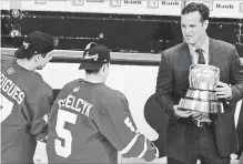  ?? ASSOCIATED PRESS FILE PHOTO ?? In this 2015 photo, Boston University hockey head coach David Quinn, right, hands the Beanpot trophy to Matt Grzelcyk and Evan Rodrigues, left, after their overtime win against Northeaste­rn.