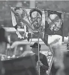  ?? GREG BAKER/AFP/GETTY IMAGES ?? A South Korea protester displays images of North Korean leader Kim Jong Un, right, and predecesso­rs Kim Il Sung, left, and Kim Jong Il in April.