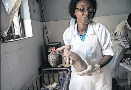  ?? Photo: Lynsey Addario/getty Images ?? Powerless: Midwife Gloria Garbor with a baby delivered at a clinic in Banki, Nigeria. The country’s power crisis puts vulnerable patients, such as premature babies, at risk.