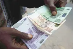  ?? — Reuters ?? A trader displays new Congolese currency bills in the Democratic Republic of the Congo's capital, Kinshasa.