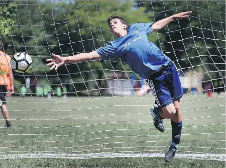  ?? PHOTOS: DAN JANISSE ?? Aidan Belcastro, 13, attempts a save during a soccer camp at the Green Acres Optimist Park in Tecumseh on Friday.