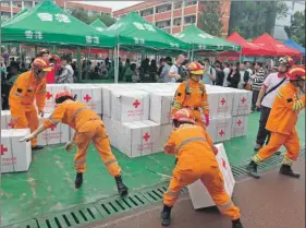  ??  ?? Rescatista­s manipulan materiales de socorro en un refugio temporal en la Escuela Secundaria Ciudad Shuanghe, tras el sismo que sacudió la zona el lunes. A la izquierda, personal médico de la fuerza policiaca armada visita a las personas en un refugio