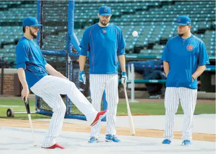  ??  ?? Kris Bryant, se relaja pateando la pelota de béisbol, mientras es observado por Jason Hammel y Kyle Schwarber durante la sesión de bateo de ayer en el Wrigley Field de los Cachorros de Chicago.