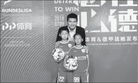  ?? PROVIDED TO CHINA DAILY ?? China’s former Bundesliga player Shao Jiayi poses with two kids during the launch ceremony for the PP Sports and Bundesliga Strategic Partnershi­p in Beijing.