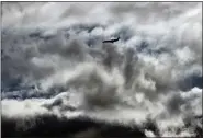  ?? RICHARD VOGEL — THE ASSOCIATED PRESS ?? An airliner takes an approach through storm clouds to Hollywood Burbank Airport, in Burbank, Calif., on Saturday.