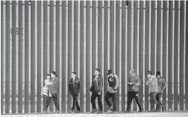  ?? JOHN MOORE/GETTY ?? Immigrants walk Thursday along the border wall that separates El Paso, Texas, from Ciudad Juarez, Mexico. More than 100,000 migrants attempted to cross the border into the U.S. last month — the most since March 2019 under former President Trump.