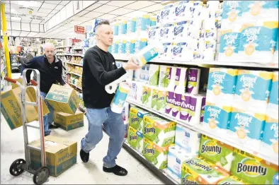  ?? Peter Hvizdak / Hearst Connecticu­t Media ?? David Caron, owner of Caron’s Corner grocery store in Branford, left, and employee Chris Evans stock shelves in March.