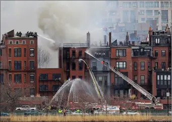  ?? STUART CAHILL — BOSTON HERALD, FILE ?? Fire crews can be seen in a massive response to the fatal 9-alarm fire on Beacon Street in Boston, as seen in this photo taken from Cambridge on March 26, 2014.