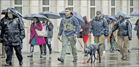  ?? Drew Angerer Getty Images ?? A U.S. MARSHAL patrols with a dog outside the courthouse recently. Inside, National Guard specialist­s scan for a wide variety of threats.